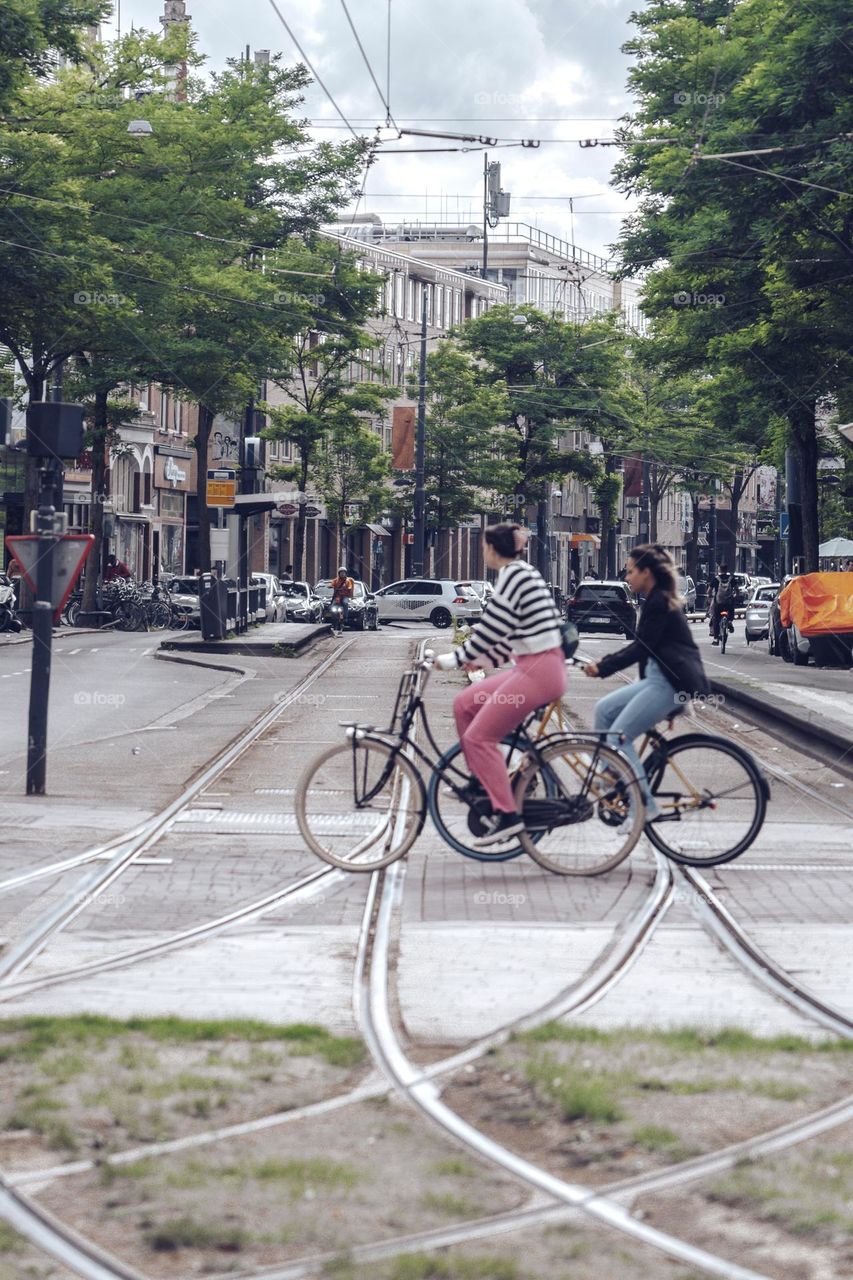 Two ladies riding bicycles across the tram tracks