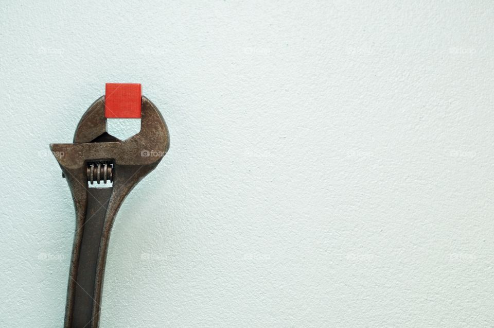 Adjustable spanner (adjustable wrench) holding a red wooden block.