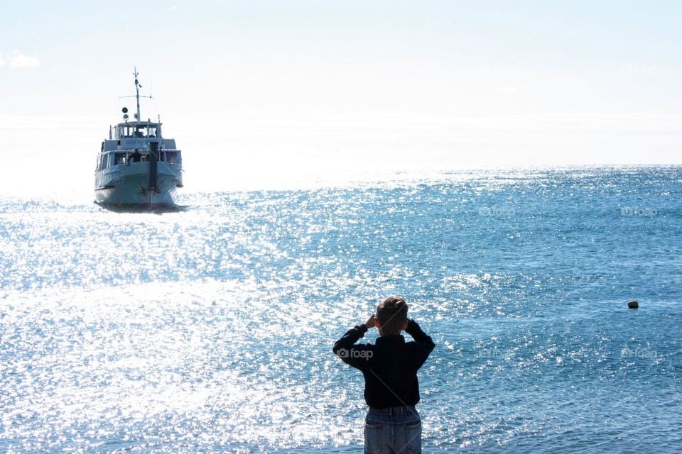 Boy looking at ferry at the seaside 