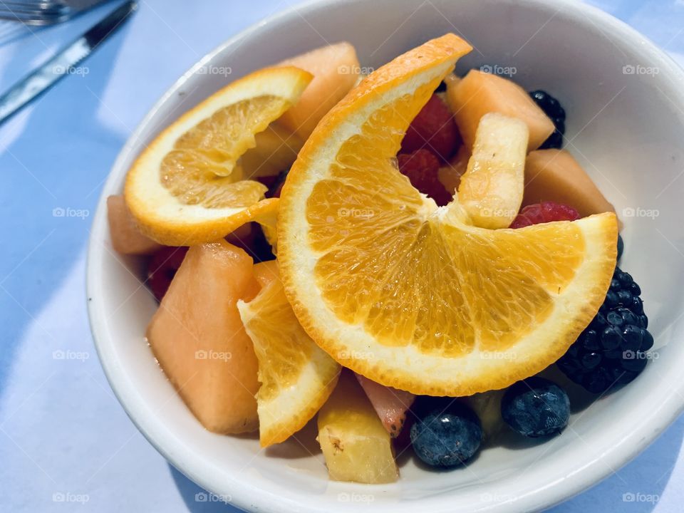 Bowl of fruit for breakfast with oranges, melons and berries 