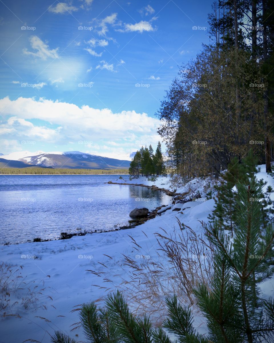 A snowy landscape around the lake and mountains.