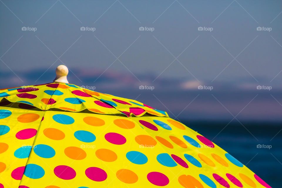 Yellow polka dot umbrella chilling seaside on the beach enjoying the refreshing sea breeze 