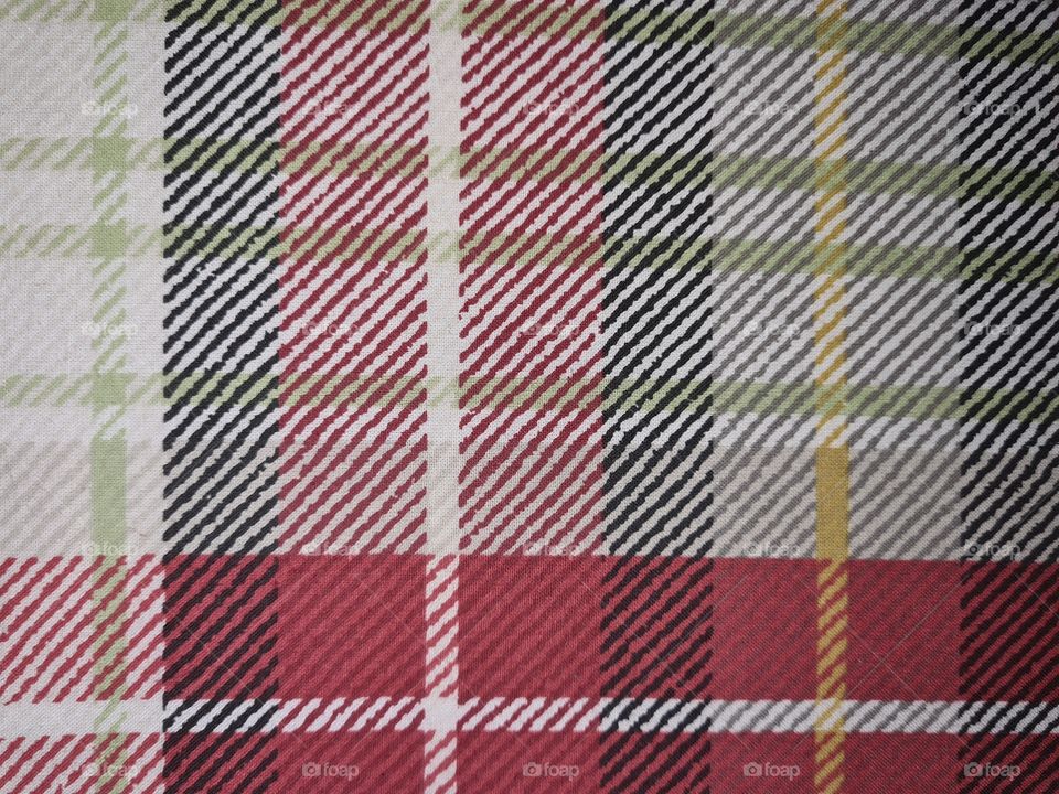 Scottish-like squares and check pattern of a fabric in green, yellow, red, white and dark blue colors.