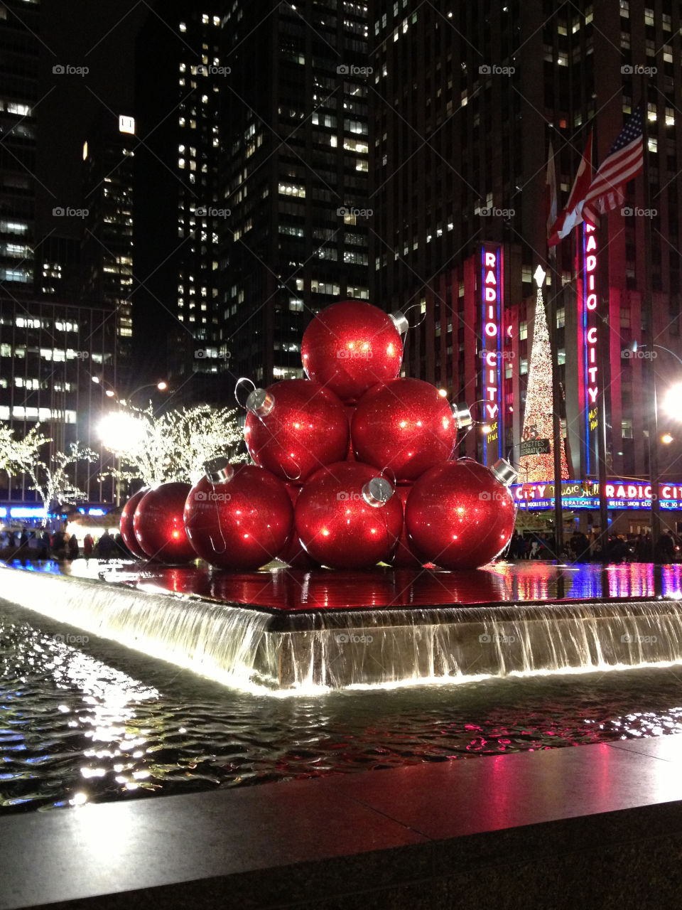 A pile of big red ornaments on a water fountain by Radio City Music Hall in New York City at Christmas time