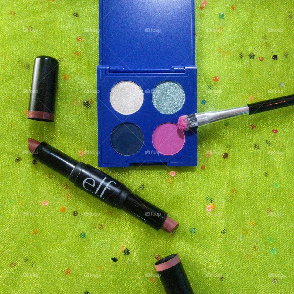 A small blue eyeshadow palette, with a brush and lipstick.