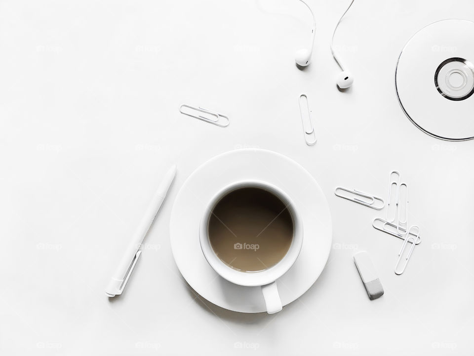 White office supplies and white cup of coffee with milk on white desktop 