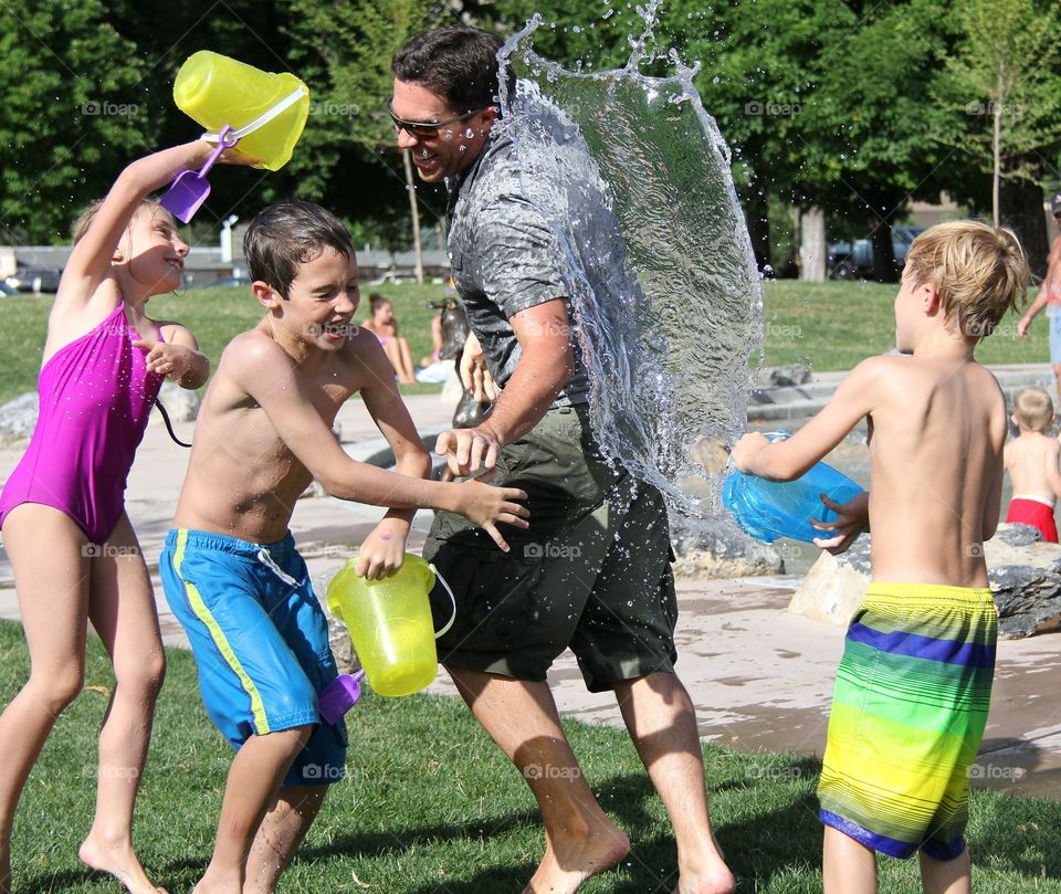 Very hot summer. children play throwing water at a parent.