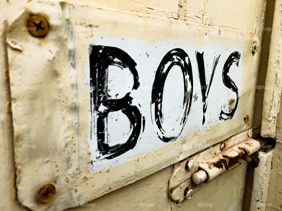 Old rusted painted tin sign on old door marked BOYS. Outdoor loo, outdoor John, outdoor toilet