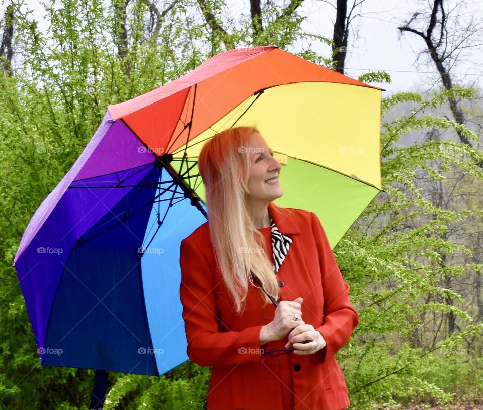 Woman with a rainbow colored umbrella on a rainy day 
