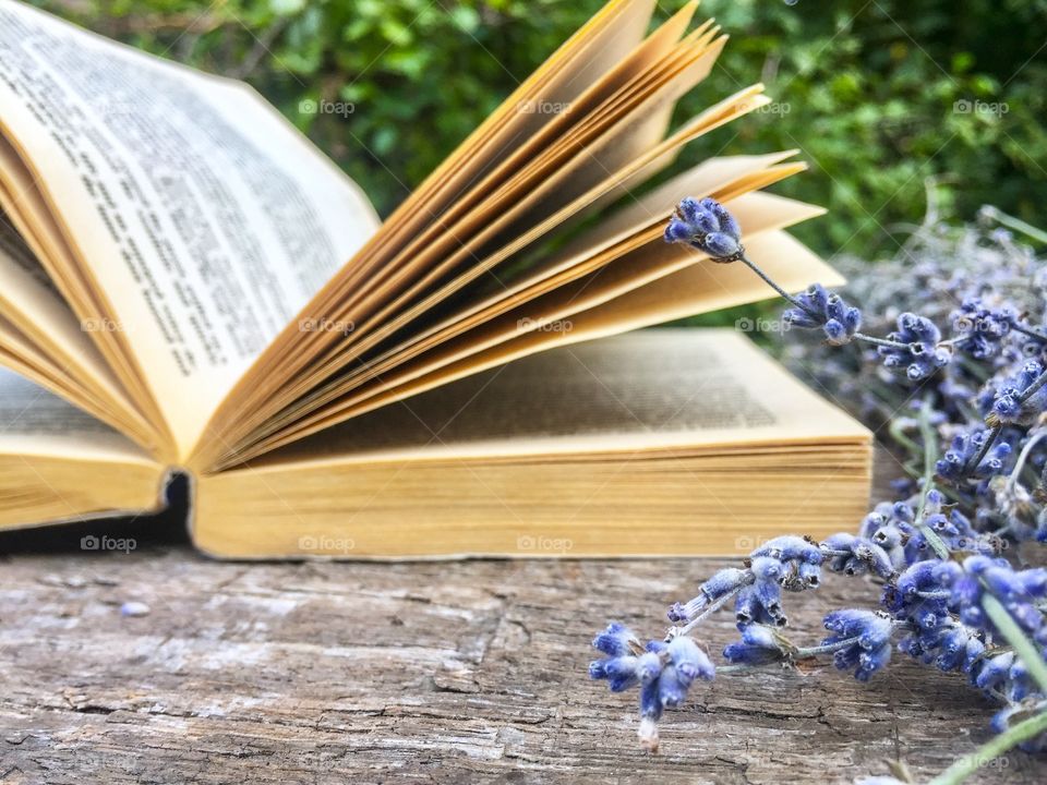 Open book on wooden table with lavender beside