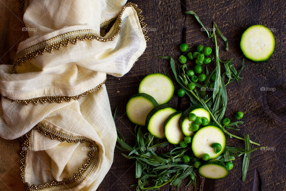 Cooking at home fresh cut zucchini green peas and tarragon on rustic wood with table linen 