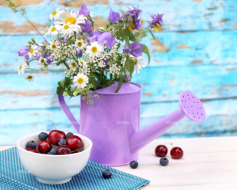 summer bright still life with a bouquet in a watering can and berries