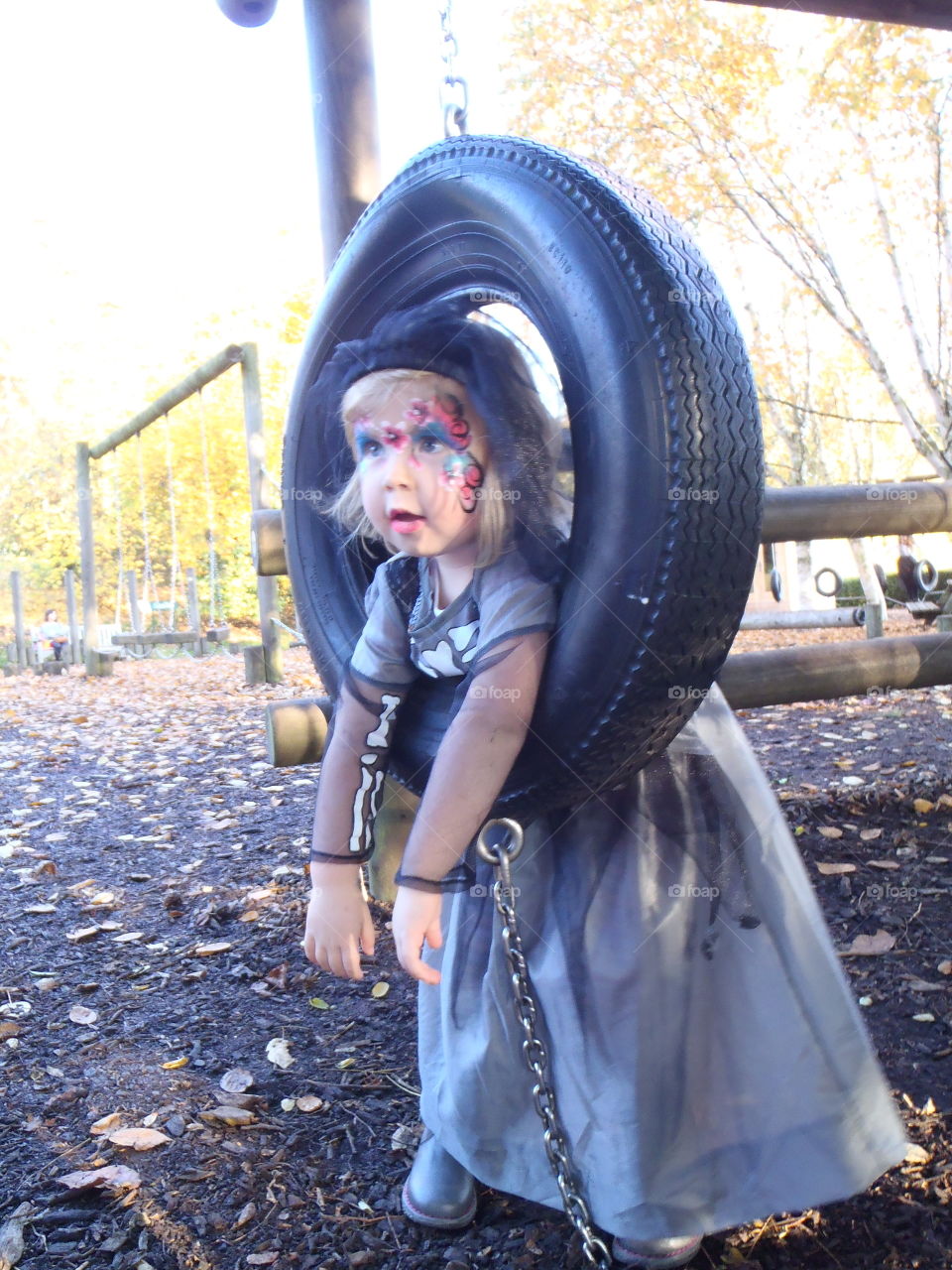 Little girl on tire swing with face paint