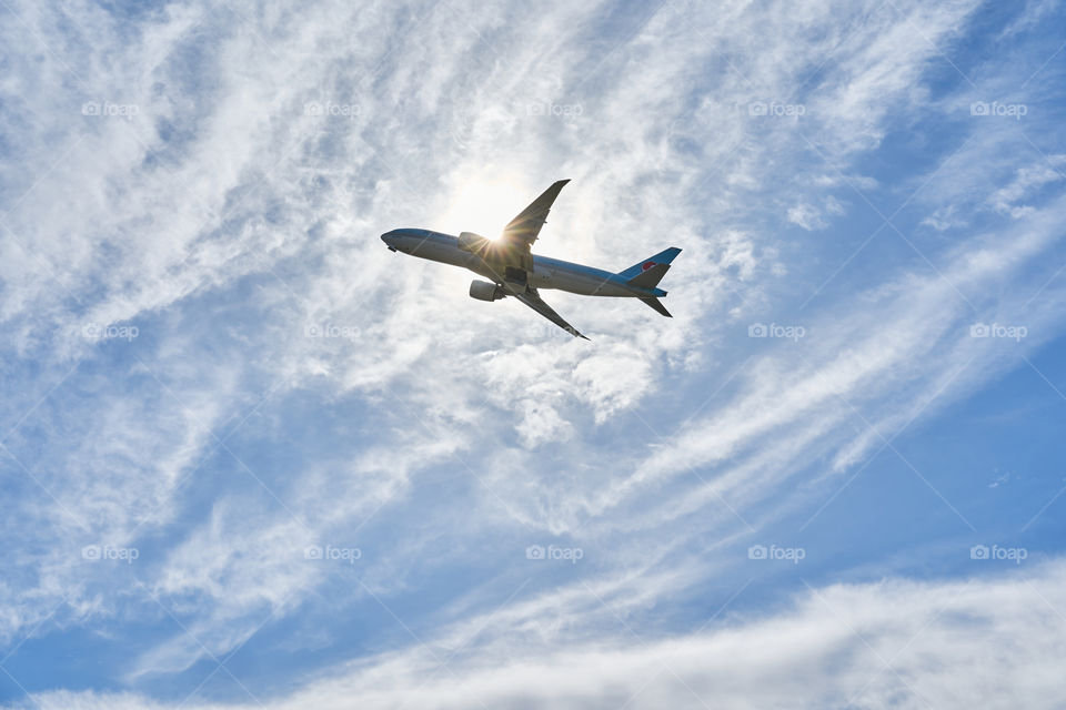 Plane flying through a blue cloudy sky