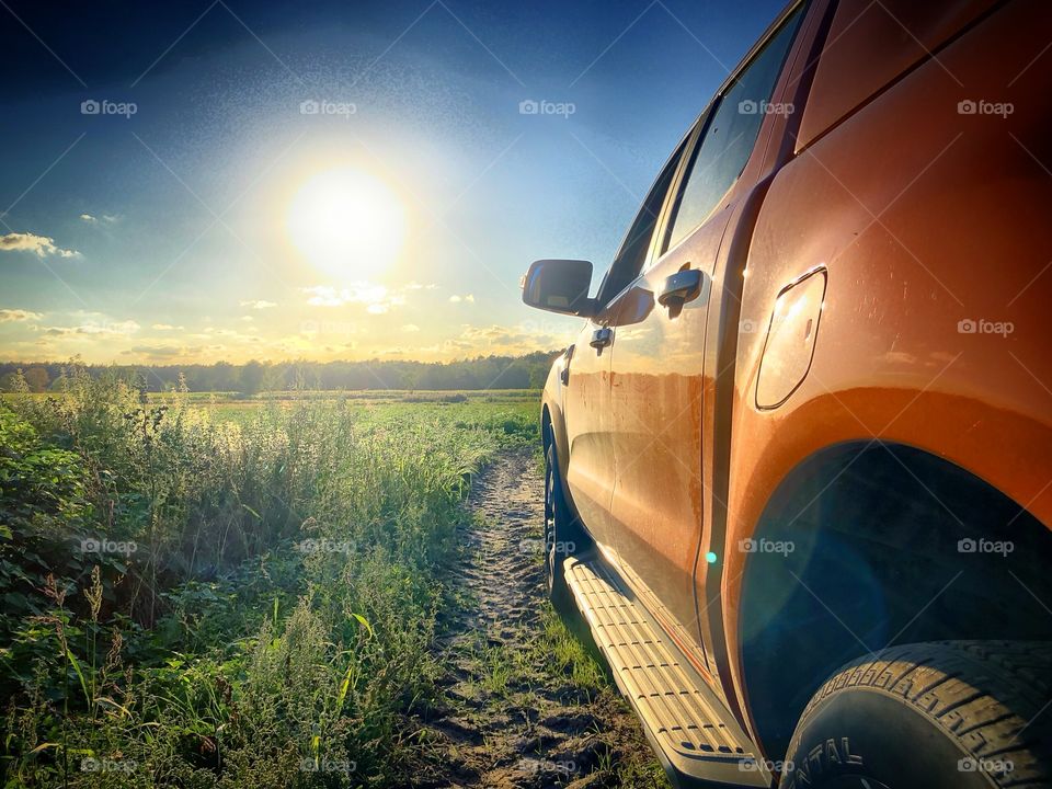 A 4x4 pickup truck in an rural off road path against a sunset