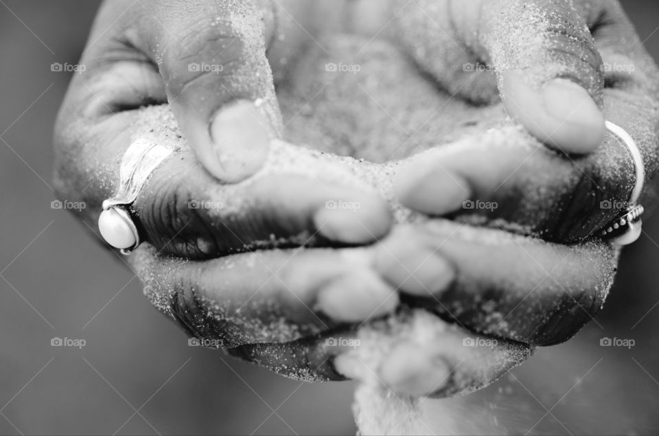 A woman squatting on Tybee beach has sand pouring through her hands.