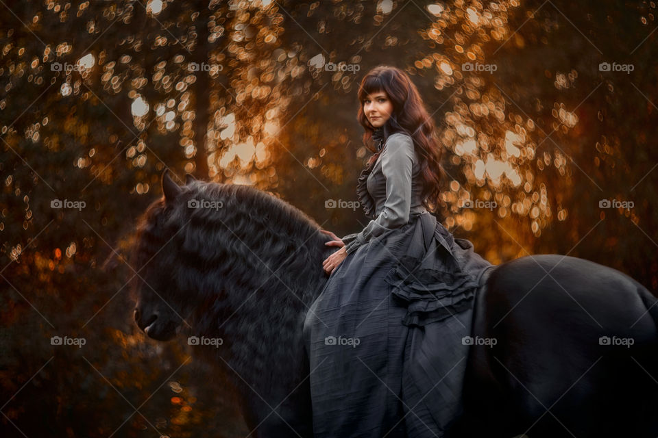 Beautiful young woman on black stallion 
