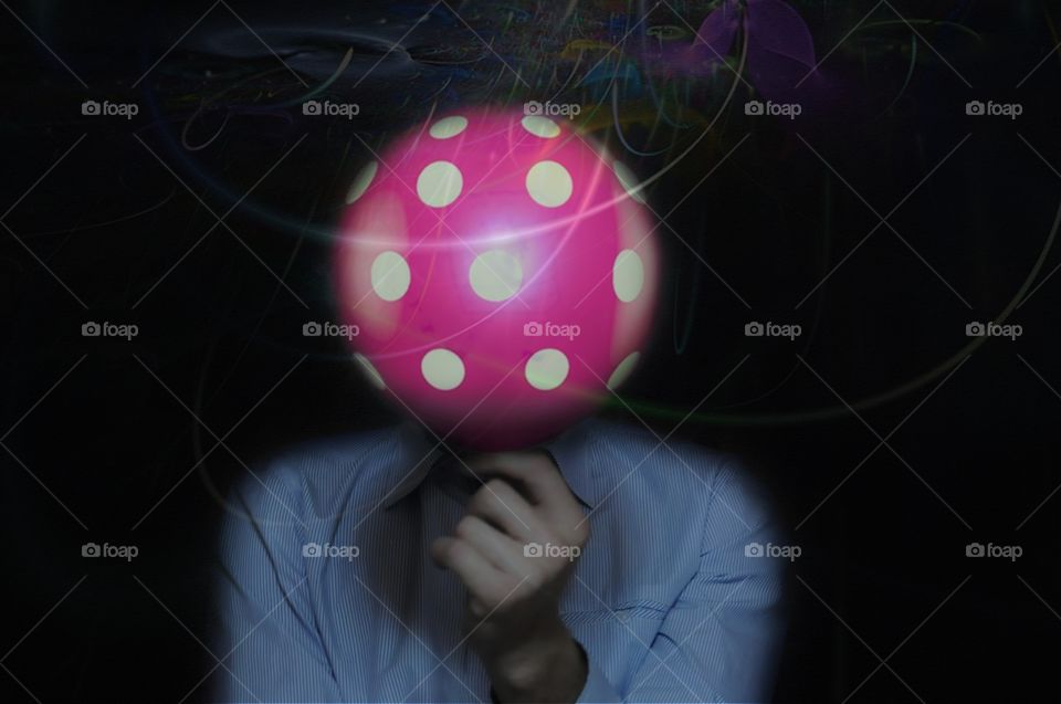 behind balloon. businessman hiding his face behind a luminous pink balloon