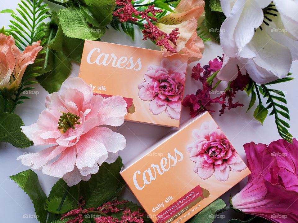 Two single soap bars of the new Caress surrounded by matching floral on a white background.