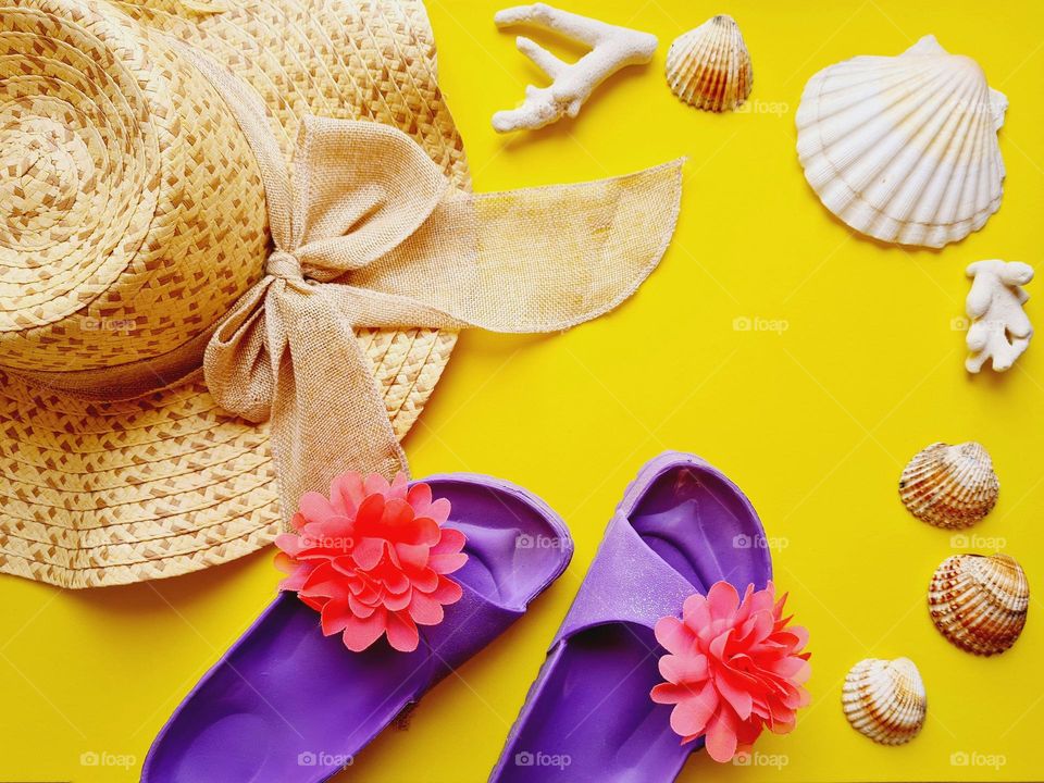 purple beach slippers and other accessories on yellow background