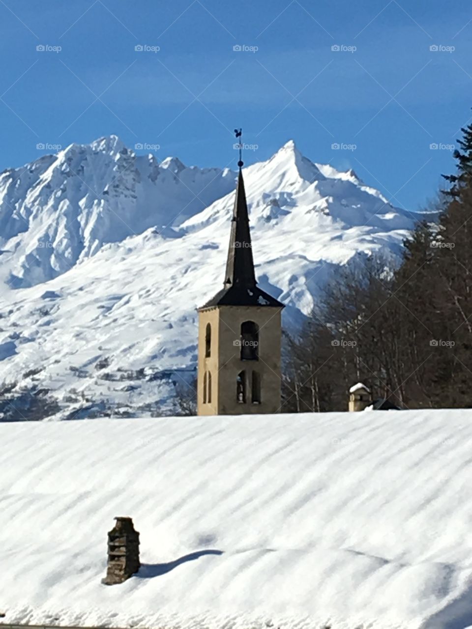 Snowy mountains behind church of a village