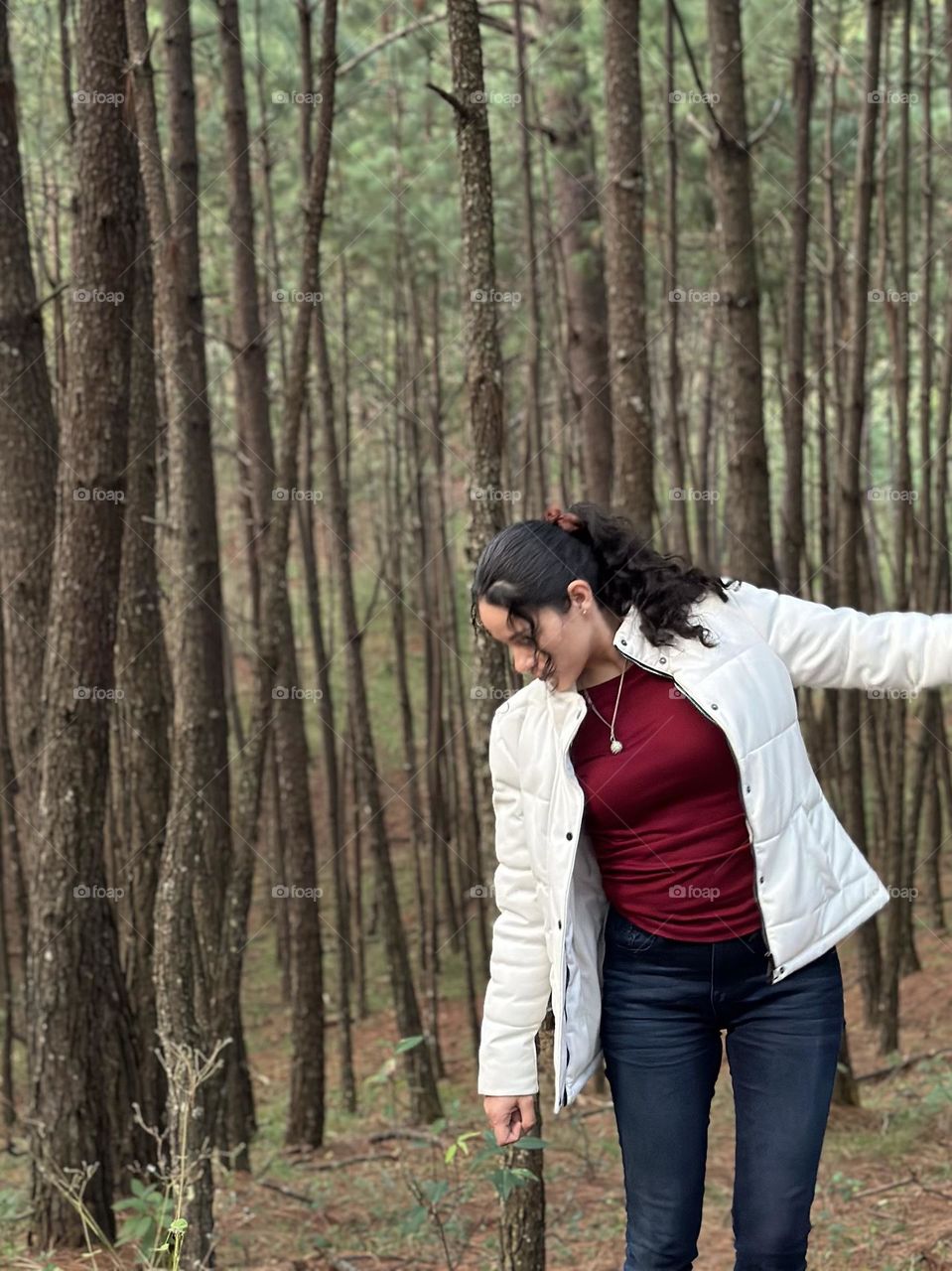 Portrait of woman walking in the middle of the forest, while looking a flowers on the ground.