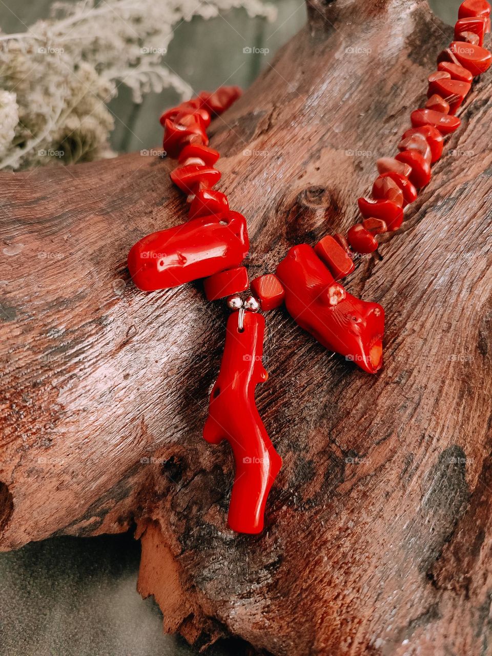 Red coral necklace on wooden log close up
