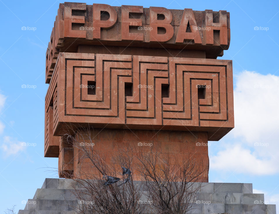 Yerevan, Armenia - April 3, 2017: Gigantic red stone sign / sculpture welcoming visitors to Yerevan by side of the M4 road to the north towards Sevan region on parly cloudy early April day.
