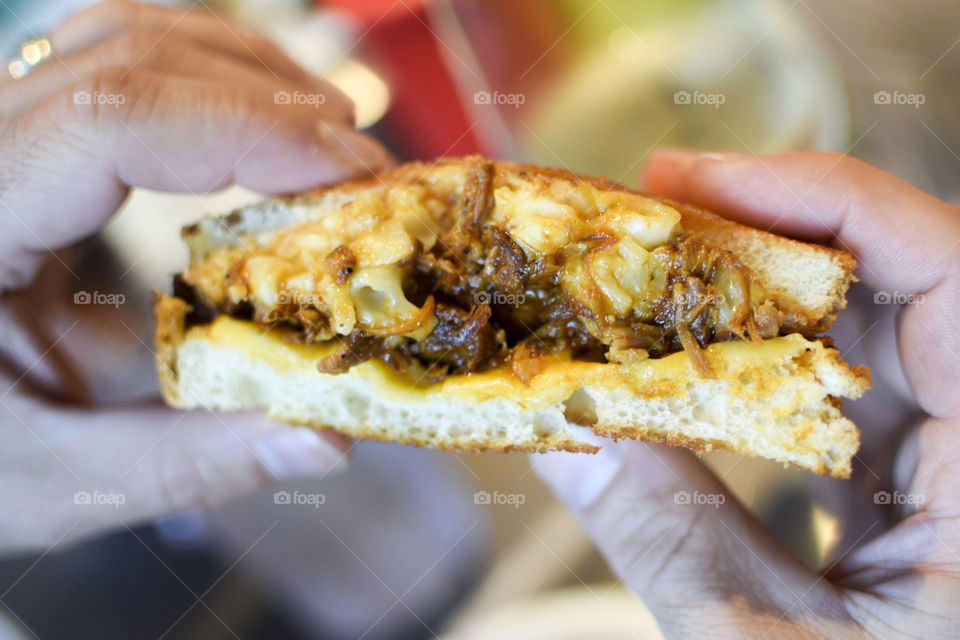 About to take a bite of a grilled cheese and pulled pork sandwich 