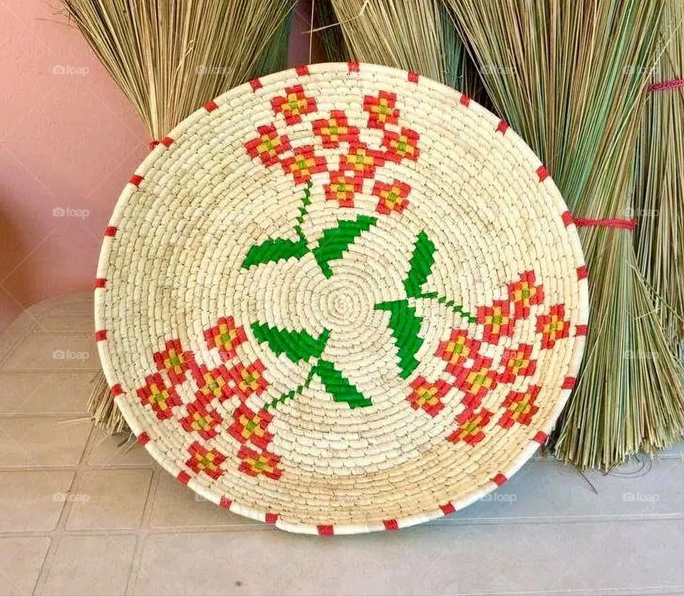 The image shows a group of hand -made dishes of wicker, decorated with colored embroideries with beautiful floral shapes, and is elegantly displayed in a warm corner that combines heritage and beauty, which gives the place an artistic spirit and attr