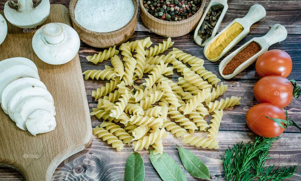 Raw pasta with ingredients and wooden accessories