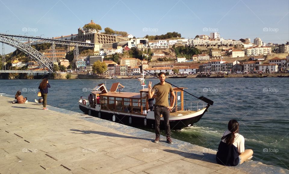 A Gui near a typical português boat on a river in Porto, Portugal