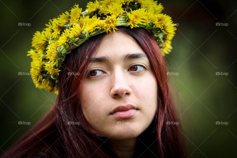 Beautiful young woman in yellow dandelion wreath