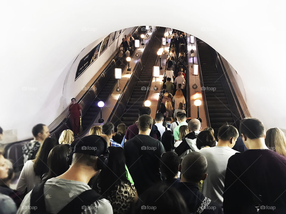 Crowd walking through the subway tunnel by escalator 