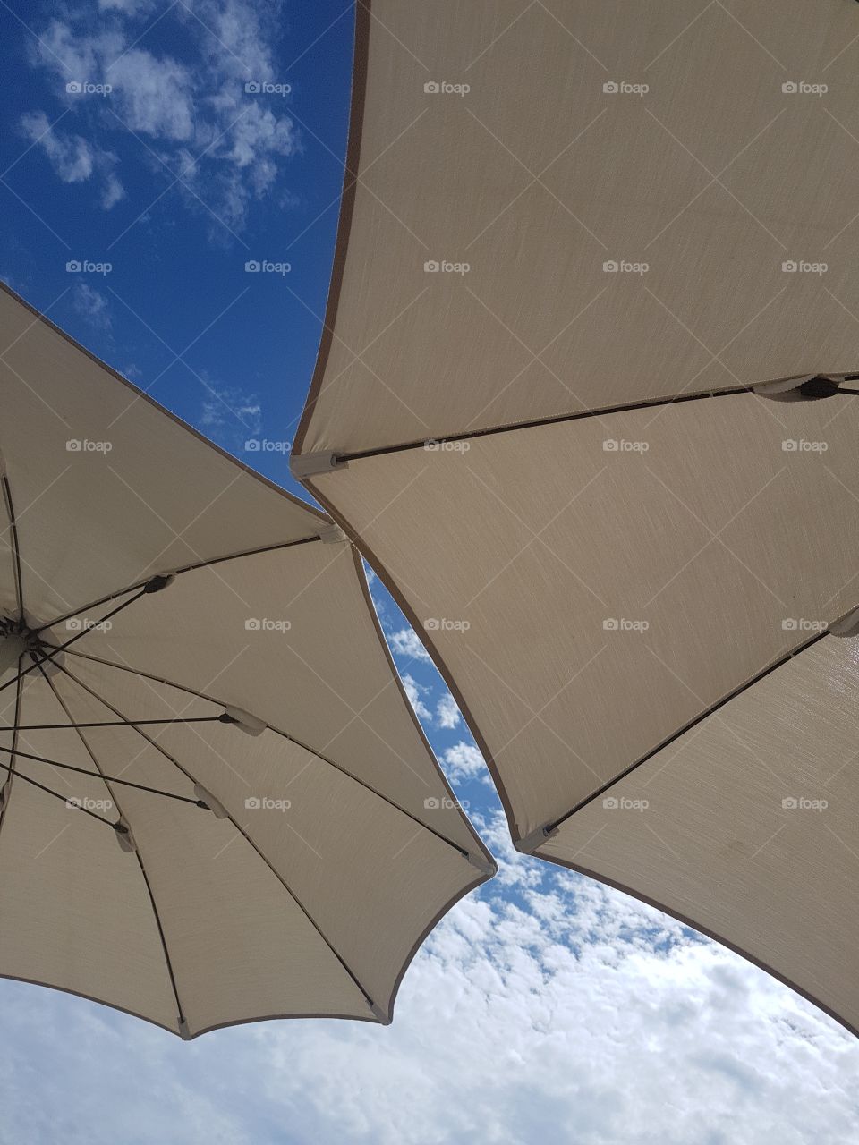 White beach umbrellas against blue sky in summertime