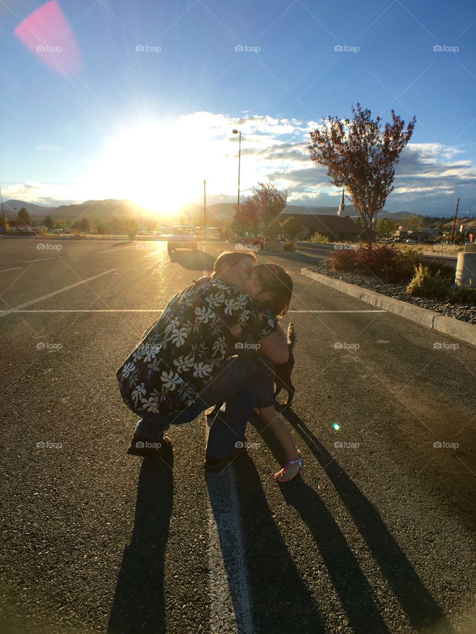 Father hugging her daughter with dog in street