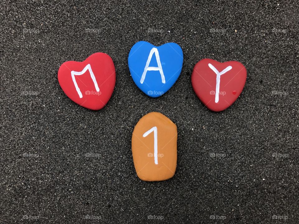 1 May, calendar date with colored stone hearts over black volcanic sand