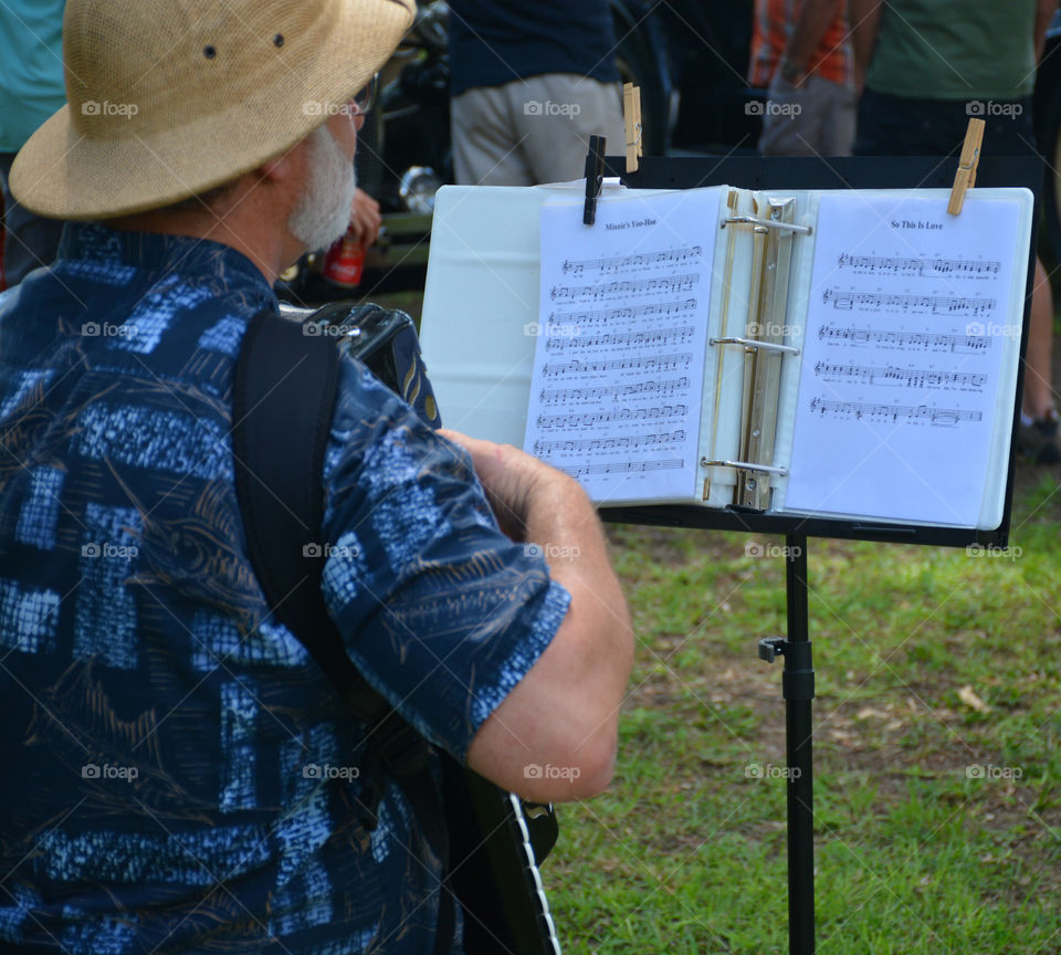 While playing his accordion, this man reads his sheet music while entertains the festival goers!