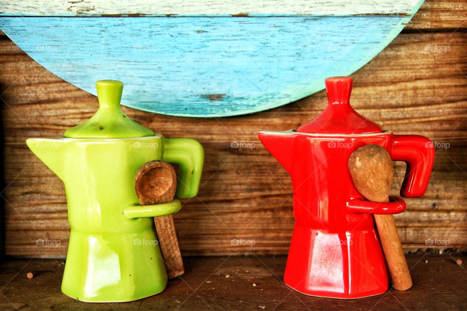 Two green and red jars with two small wooden scoops were placed side by side on the wooden floor. Has a colorful wooden background.