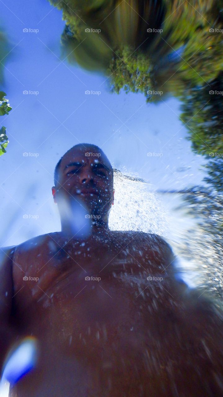 young man under the shower on the beach