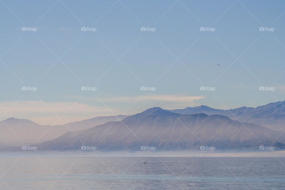 Mountain range seen in the distance across the Salton Sea in Riverside and Imperial counties, with the mist rising off the water giving a watercolor effect 