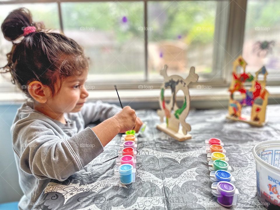 Toddler girl paints skull for Halloween, toddler does crafts for fall time, painting skulls for decoration, making homemade decorations 