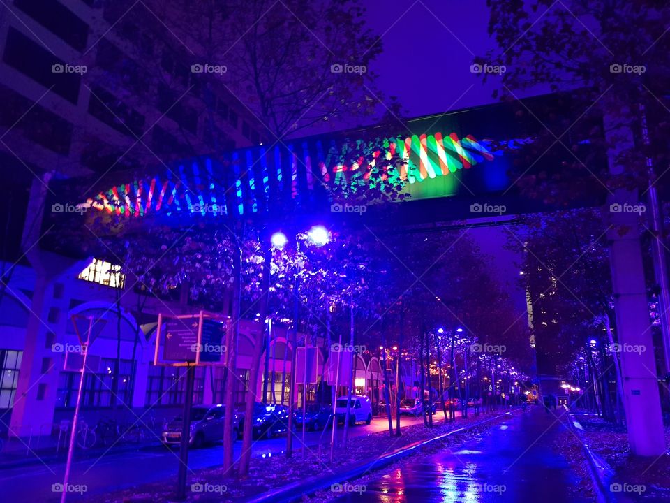 Colorful bridge over a street that is bathed in bright blue light during the GLOW festival