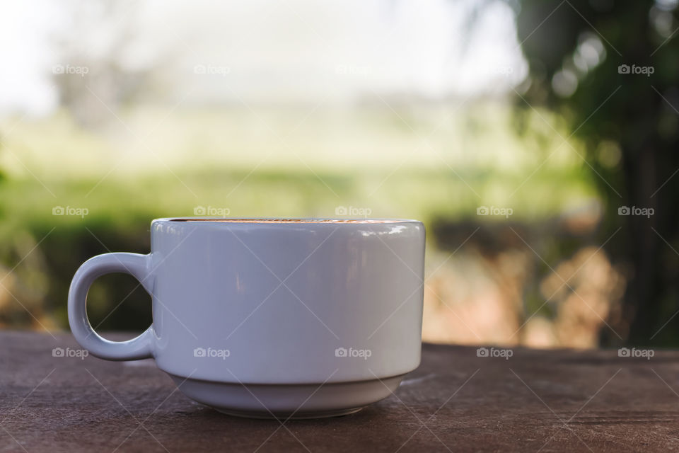 Cup of hot coffee  on wooden floor and nature background vintage style