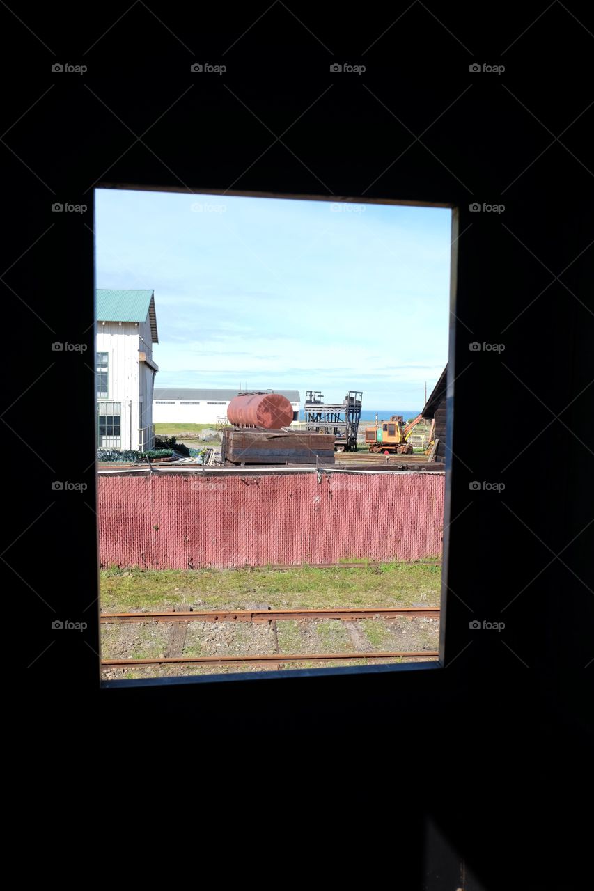 View outside the train window, coastal town, old junk industrial equipment