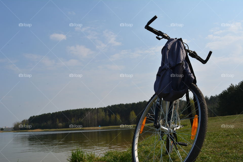bike and backpack on a lake shore travel concept