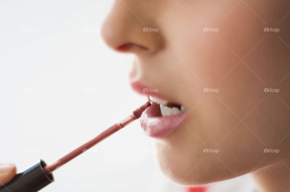 Girl painting lips with a liquid lipstick