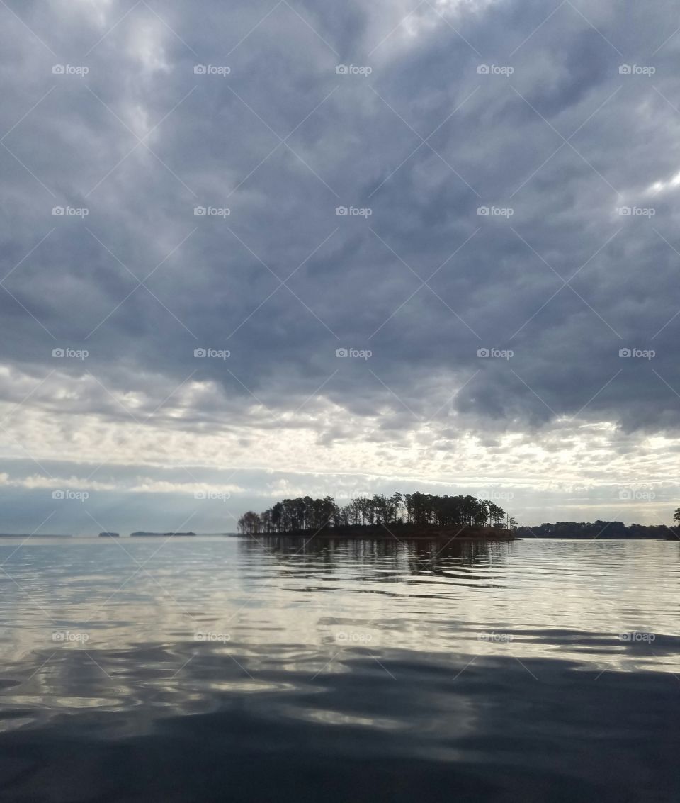 grey clouds on grey lake with an island as a contrast