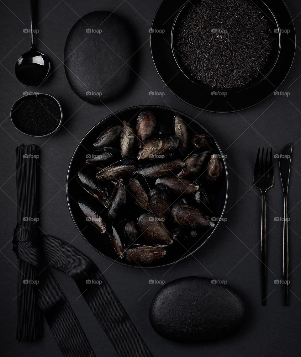 Black food on black plates on black background.