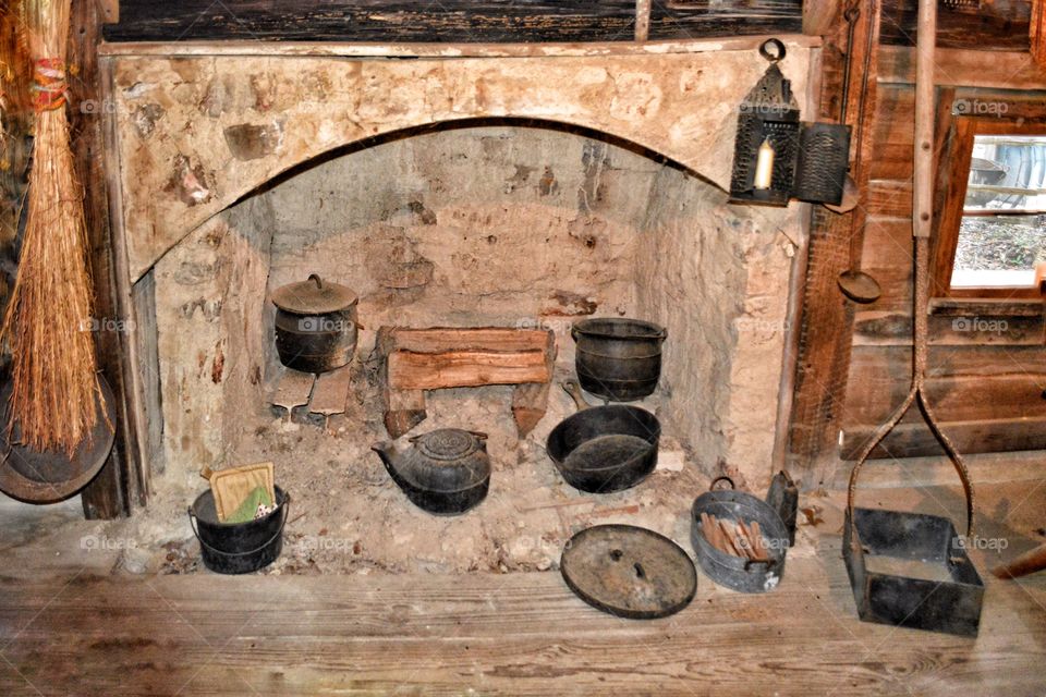 Antique cookware in a fire place. Iron pots, skillet and a hanging light